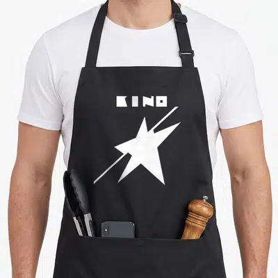 Wiktor russia apron - White KINO text above a star with a diagonal slash — shown on a black cotton canvas apron against a white background