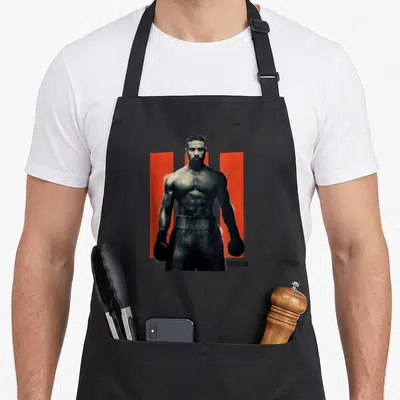 Son apollo apron - Black and white boxer photo between two red vertical bars with CREED III text — shown on a black cotton canvas apron against a white background