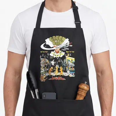 Dookie band apron - Green Day Dookie cartoon rocket explosion dogs and people print — shown on a black cotton canvas apron against a white background