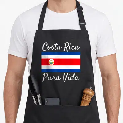 Costa beautiful apron - Costa Rica flag with arched Pura Vida text in blue white and red — shown on a black cotton canvas apron against a white background