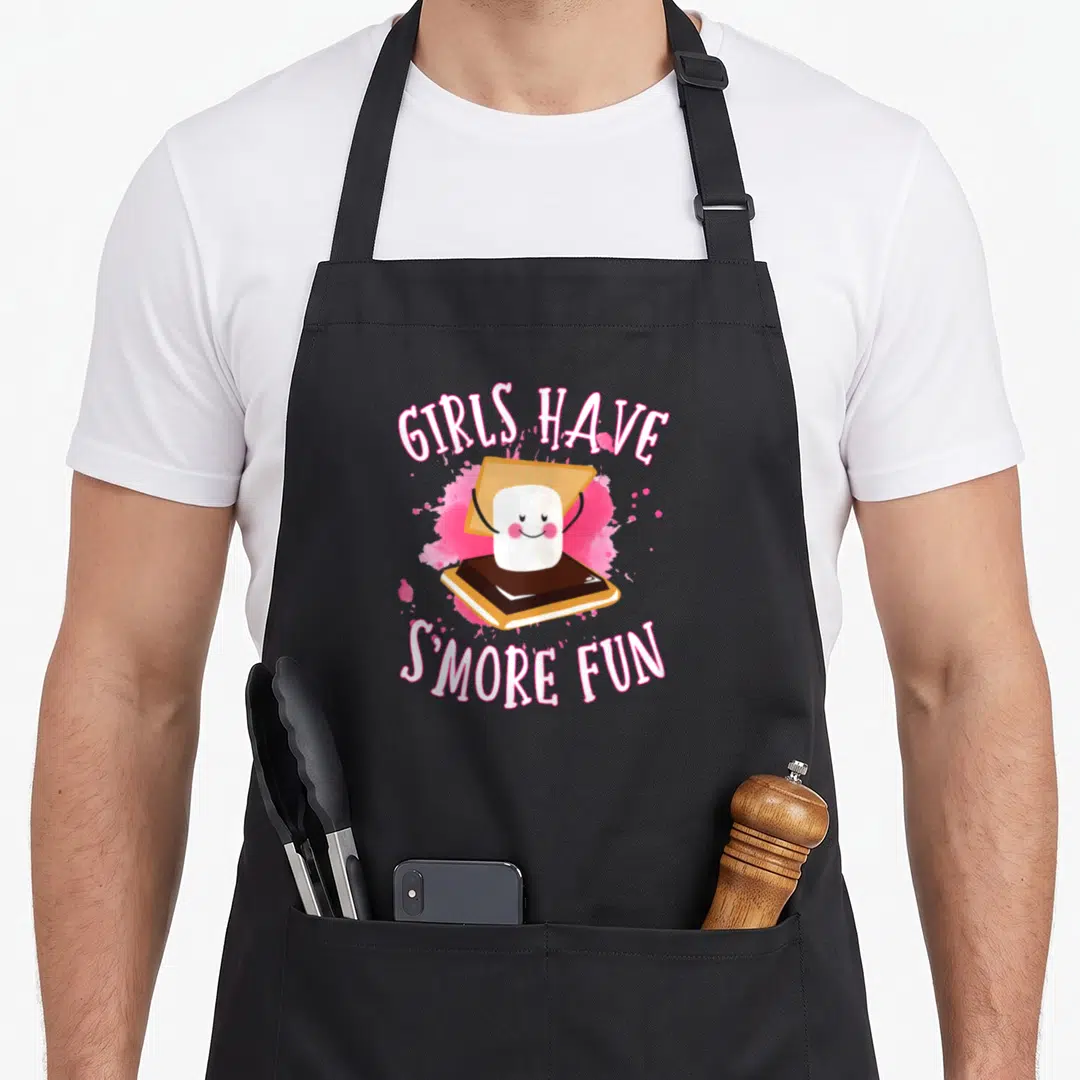 Smore camper camping apron - Cartoon s'more with pink splatter and text Girls Have Smore Fun — shown on a black cotton canvas apron against a white background
