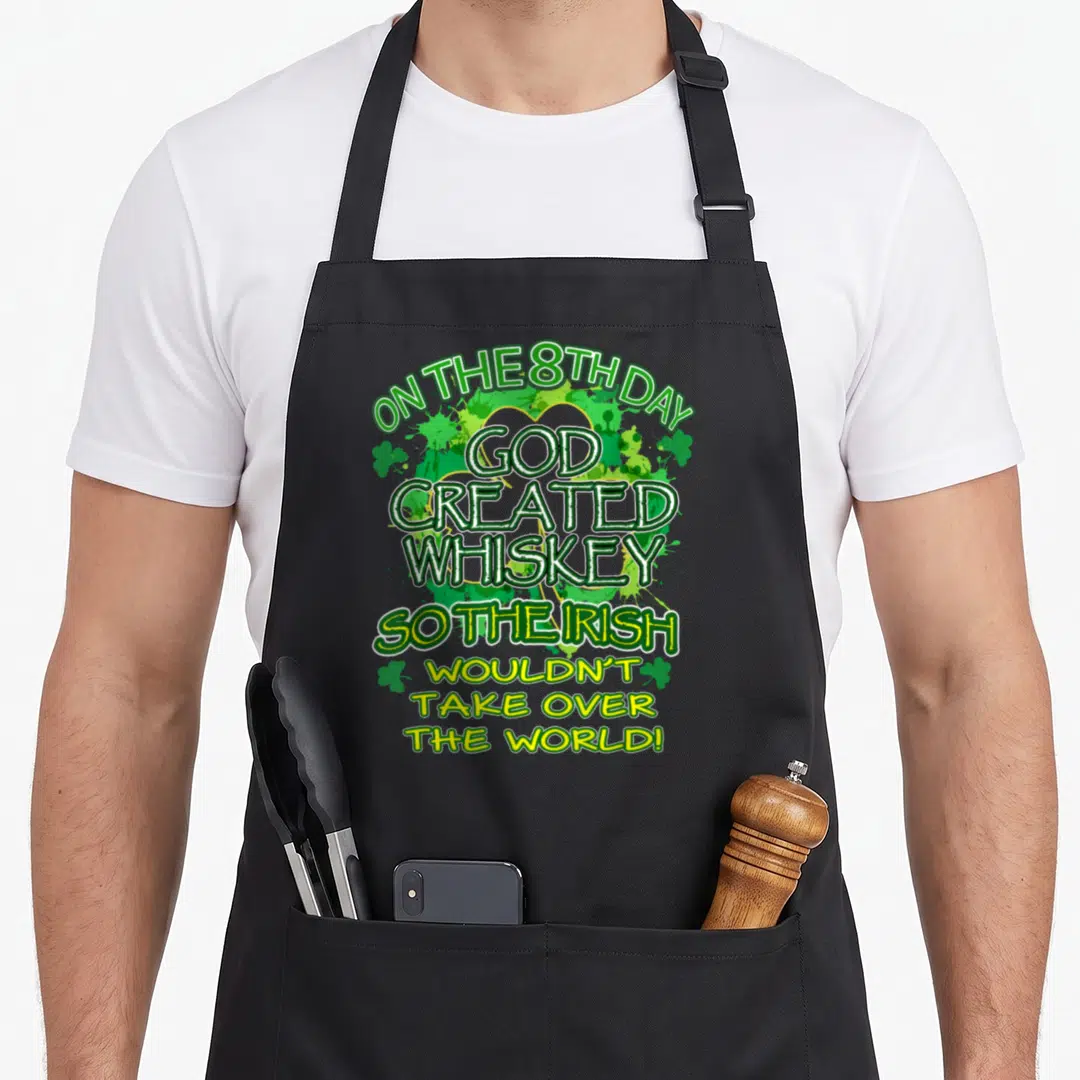 Created funny irish aprons - Green white and yellow text saying On The 8th Day God Created Whiskey So The Irish — shown on a black cotton canvas apron against a white background