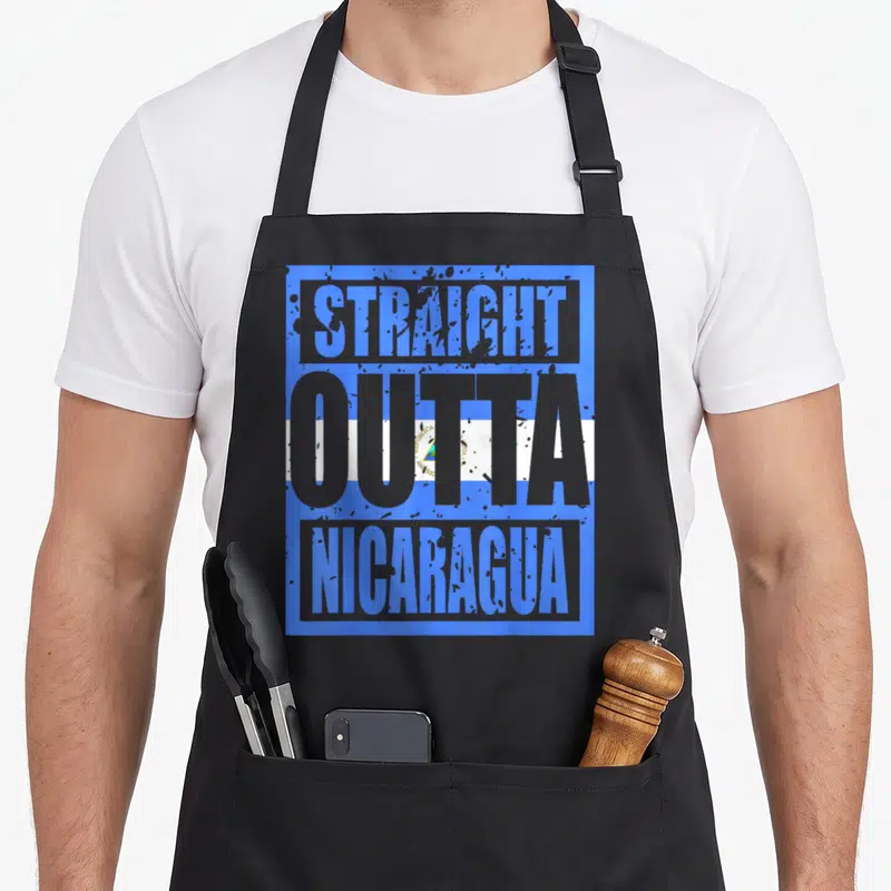 Straight nicaragua apron - STRAIGHT OUTTA NICARAGUA text in grey and blue over a rectangular flag background — shown on a black cotton canvas apron against a white background