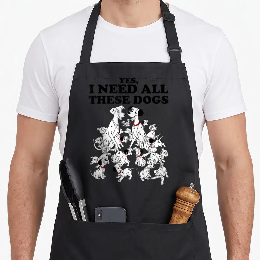 Dalmatian dog apron - Yes i need all these dogs text above cartoon dalmatians with red collars — shown on a black cotton canvas apron against a white background