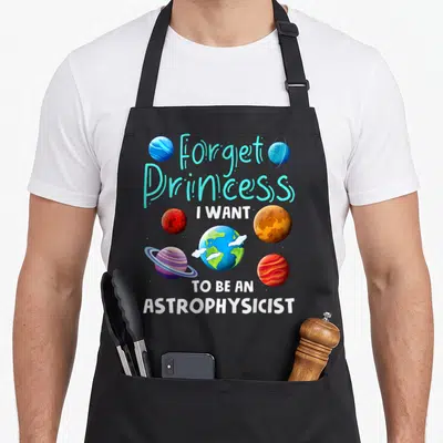 Space princess apron - Cartoon planets in cyan white blue orange red with text Forget Princess I Want To Be — shown on a black cotton canvas apron against a white background