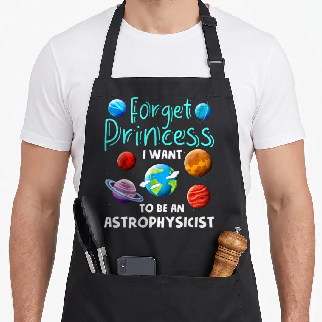 Space princess apron - Cartoon planets in cyan white blue orange red with text Forget Princess I Want To Be — shown on a black cotton canvas apron against a white background