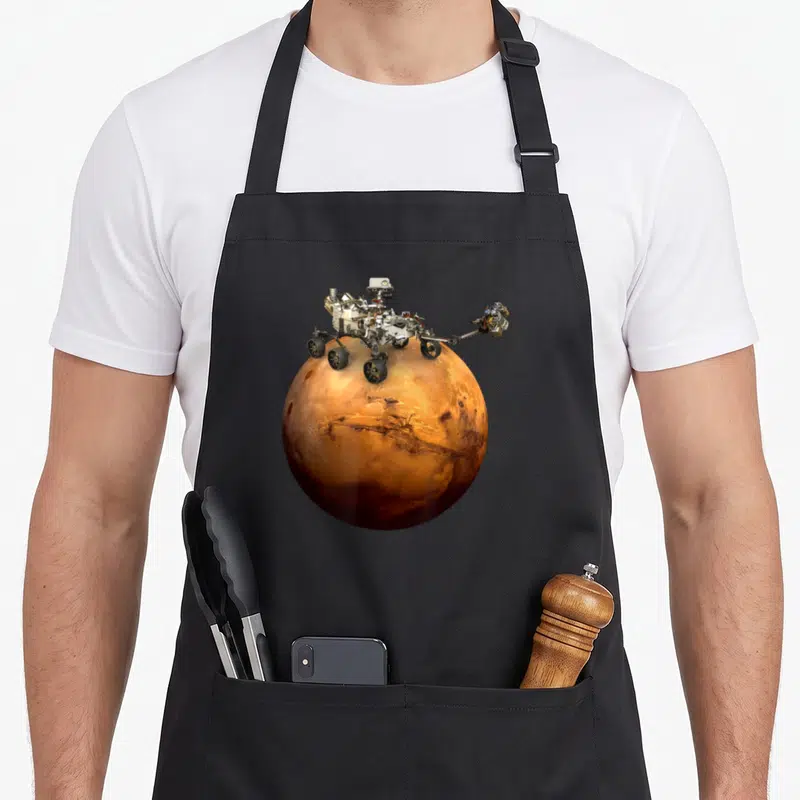 Mar rover nasa apron - Rover perched on large planet in orange, brown, white, and grey photo — shown on a black cotton canvas apron against a white background
