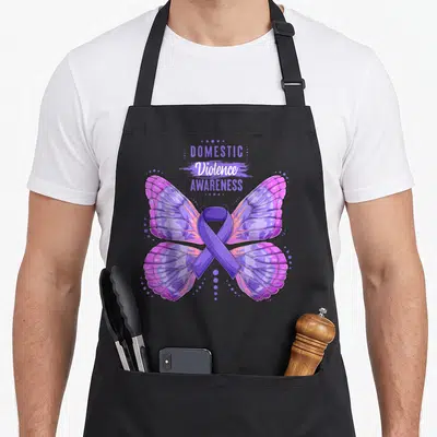 Butterfly domestic aprons - Stacked text above purple butterfly with ribbon body and surrounding dots — shown on a black cotton canvas apron against a white background