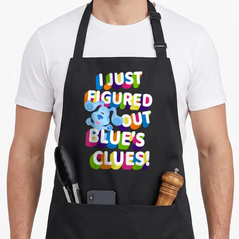 Blue colorful apron - I Just Figured Out Blue's Clues stacked text with blue cartoon dog and colorful shadows — shown on a black cotton canvas apron against a white background