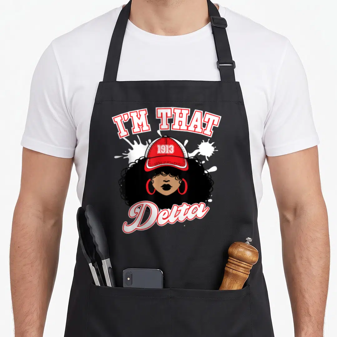 Sigma sorority apron - I'M THAT text, 1913 cap, Delta script, woman with afro and hoop earrings — shown on a black cotton canvas apron against a white background