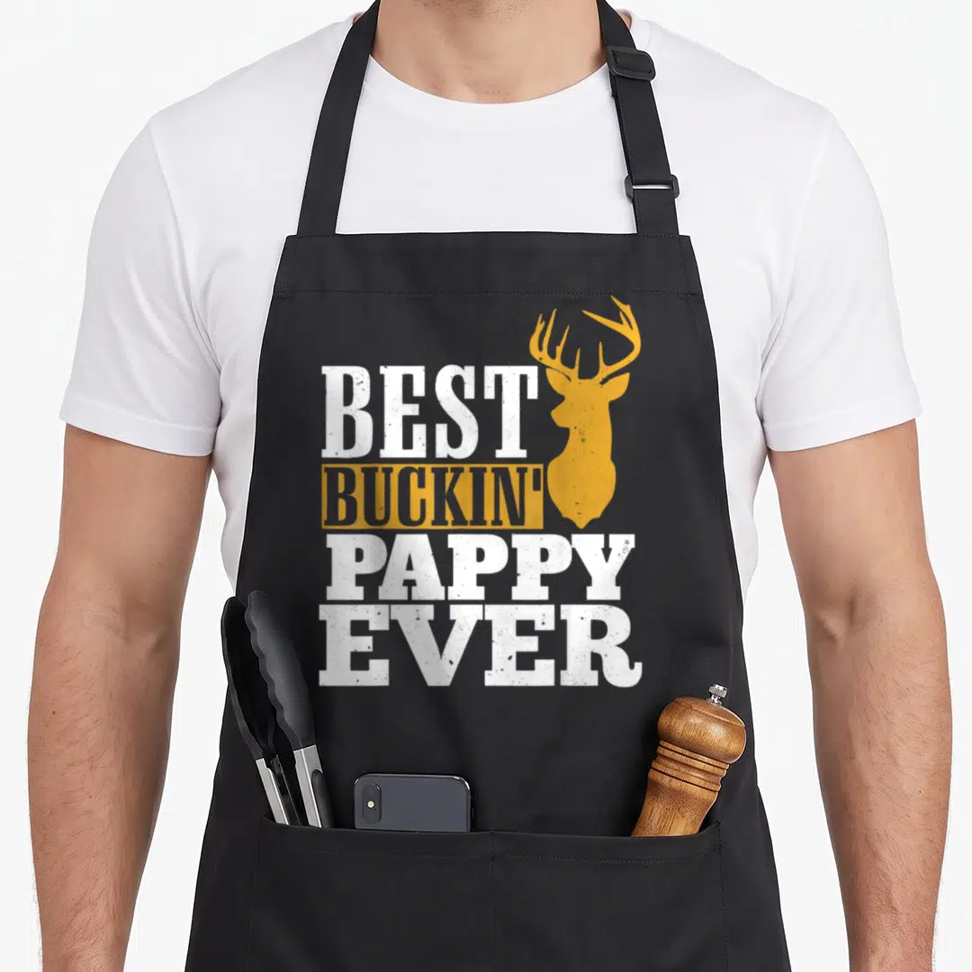 Buckin pappy apron - White and yellow-orange text Best Buckin Pappy Ever beside deer head silhouette — shown on a black cotton canvas apron against a white background
