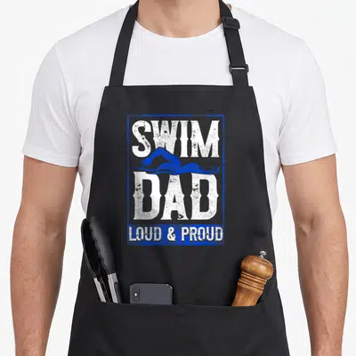 Funny swimmer swimming dad apron - Distressed white SWIM DAD LOUD & PROUD text with blue swimmer silhouette — shown on a black cotton canvas apron against a white background