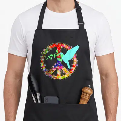 Dove colorful aprons - Multicolored floral peace sign with light blue dove carrying green olive branch in cartoon style — shown on a black cotton canvas apron against a white background