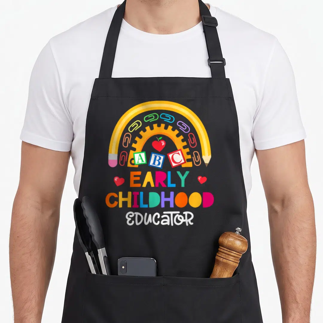 Childhood preschool teacher apron - Multicolored EARLY CHILDHOOD EDUCATOR text under yellow pencil arch with ABC — shown on a black cotton canvas apron against a white background