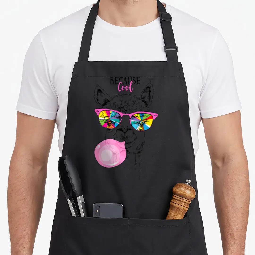 Llama rainbow apron - Line art llama head with pink sunglasses reflecting rainbow colors and blowing a pink bubble — shown on a black cotton canvas apron against a white background
