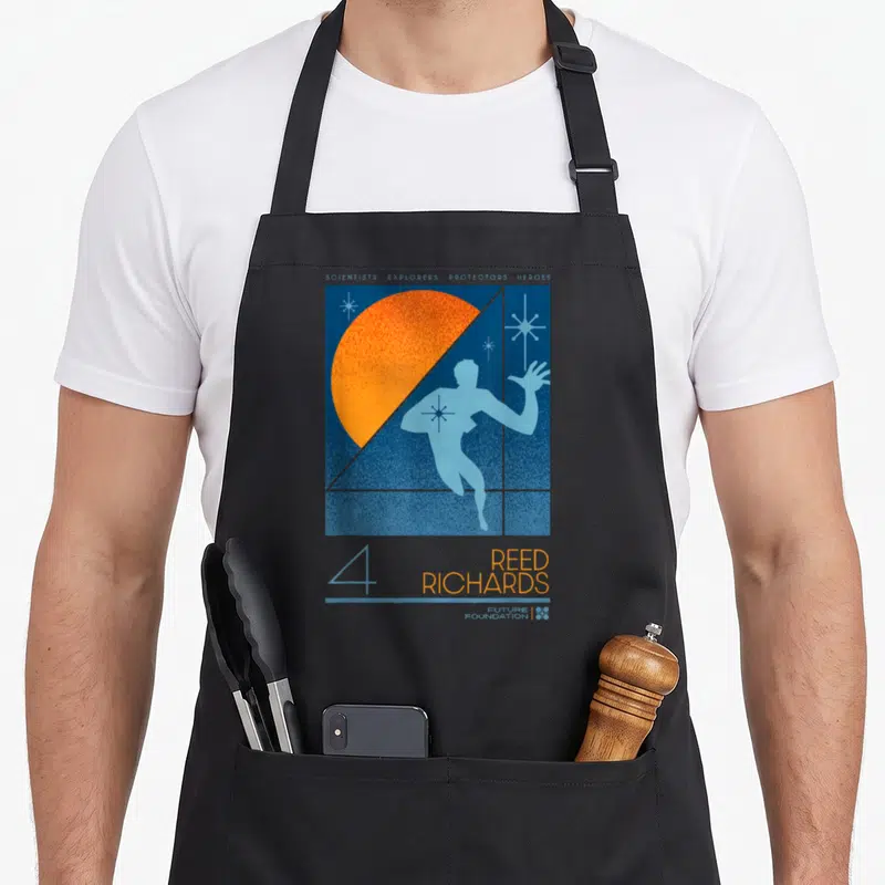 Studio future construction apron - Blue man silhouette against orange sun with Reed Richards and Future Foundation text — shown on a black cotton canvas apron against a white background