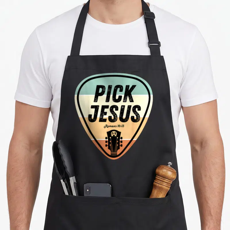 Pick jesus music christian apron - Guitar pick shape with teal orange cream stripes and PICK JESUS text — shown on a black cotton canvas apron against a white background