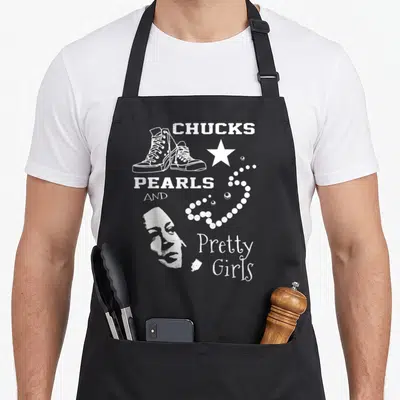 Pearl pretty apron - White line art of sneakers star and pearls surrounding woman's face with printed text — shown on a black cotton canvas apron against a white background