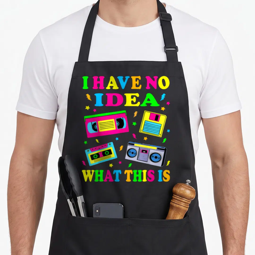 80s 90s chef outfit with apron - I Have No Idea What This Is text surrounding cassette tape, floppy disk, and boombox — shown on a black cotton canvas apron against a white background