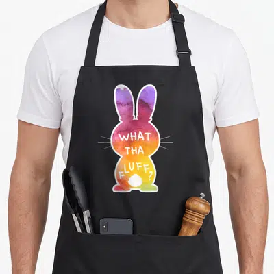 Tha easter egg apron - Rainbow tie-dye bunny with white border and text WHAT THA FLUFF? on body — shown on a black cotton canvas apron against a white background