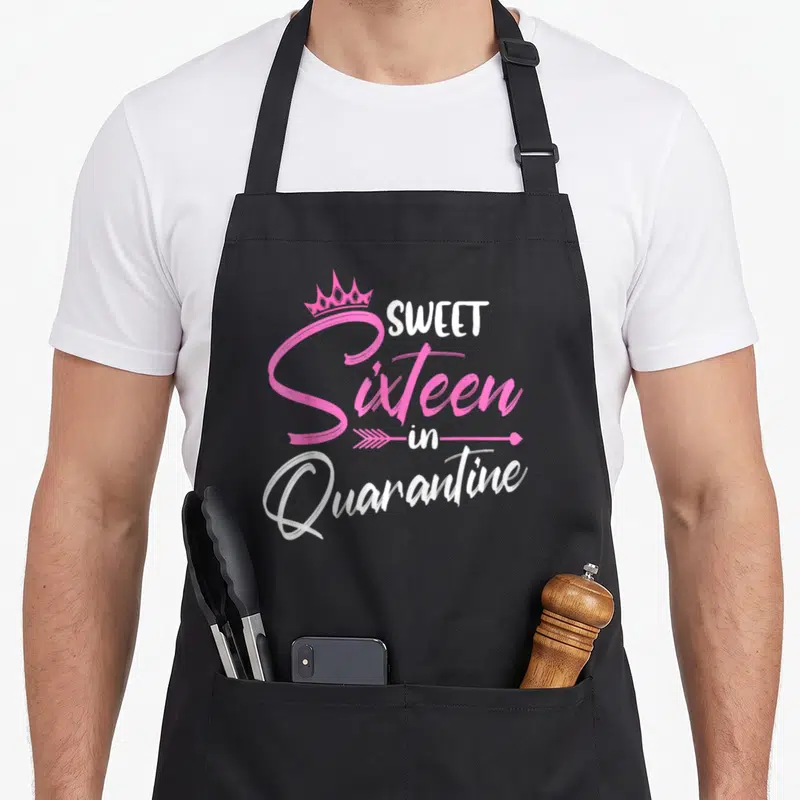 Sweet quarantine birthday apron - Pink and white text reading Sweet Sixteen in Quarantine with crown and arrow — shown on a black cotton canvas apron against a white background