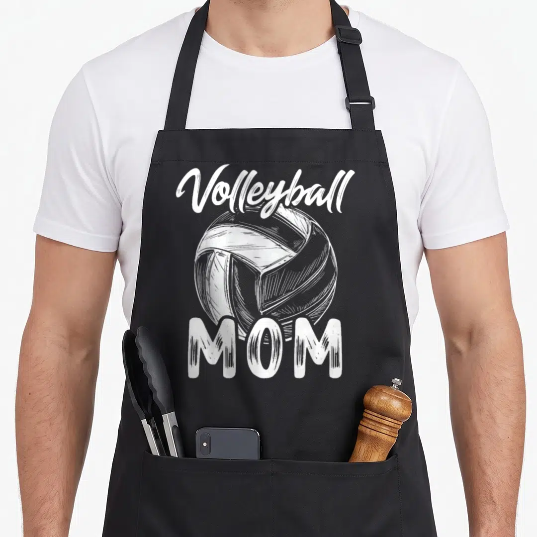Volleyball family aprons - White sketched volleyball with arched Volleyball text and block MOM letters on black fabric — shown on a black cotton canvas apron against a white background
