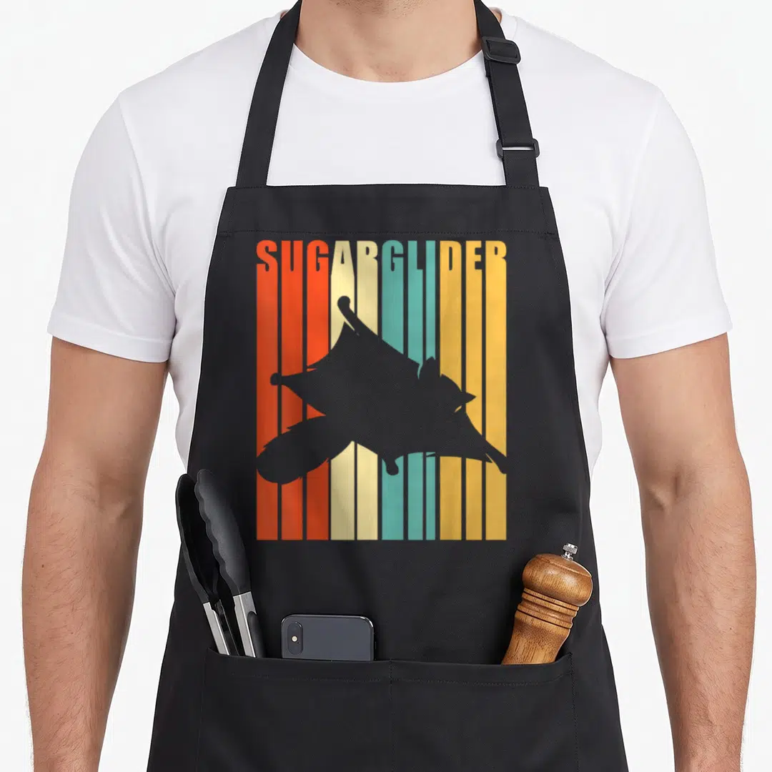 Australia sugar apron - Grey sugar glider silhouette over vertical orange teal and yellow stripes with text SUGARGLIDER — shown on a black cotton canvas apron against a white background