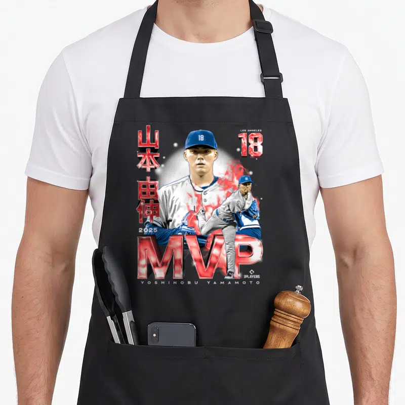 Yoshinobu baseball fan apron - Yoshinobu Yamamoto portrait with MVP text, red smoke, and Japanese characters on black — shown on a black cotton canvas apron against a white background