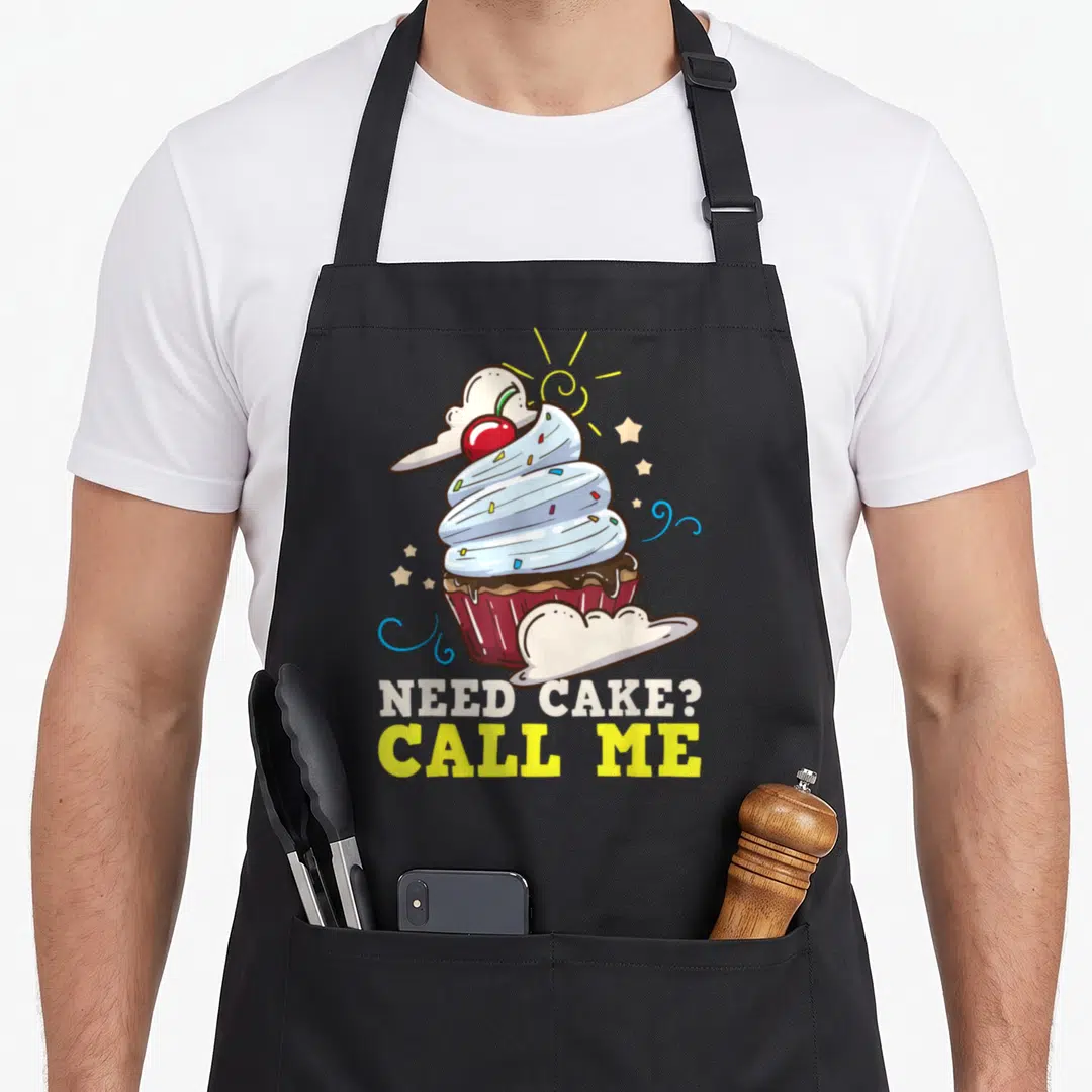 Baker cake cupcake apron - Cartoon cupcake with cherry and text NEED CAKE CALL ME — shown on a black cotton canvas apron against a white background