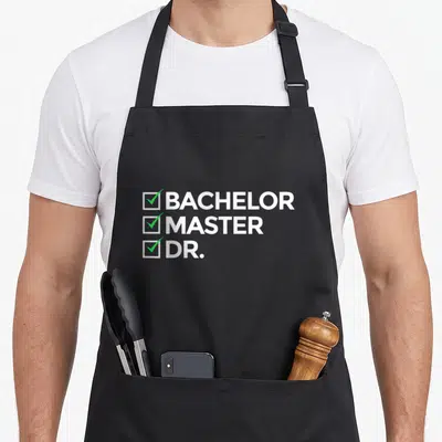 Doctorate master apron - Three stacked lines reading BACHELOR MASTER DR next to white boxes with green check marks — shown on a black cotton canvas apron against a white background