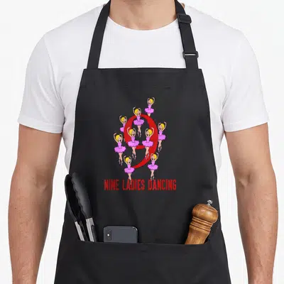 Nine ladies christmas apron - Nine pink ballerinas circling a red number 9 with red text below — shown on a black cotton canvas apron against a white background