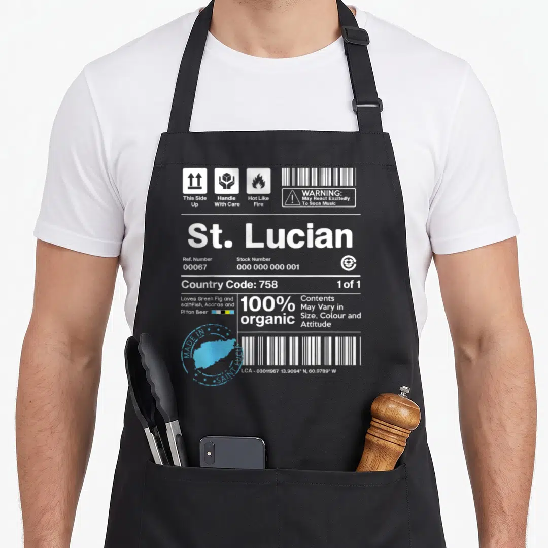 Handle saint lucia apron - Shipping label graphic with St Lucian text, blue map stamp, and Soca music warning icons — shown on a black cotton canvas apron against a white background