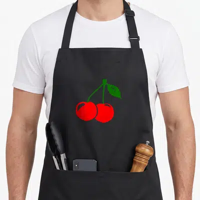 Cute cherry apron - Two red cherries on a green stem with one leaf, minimalist fruit design — shown on a black cotton canvas apron against a white background