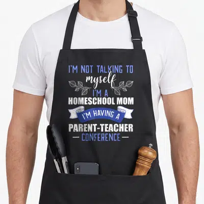 Homeschool cute teacher apron - Blue and white text reading I'm a homeschool mom having a parent teacher conference — shown on a black cotton canvas apron against a white background