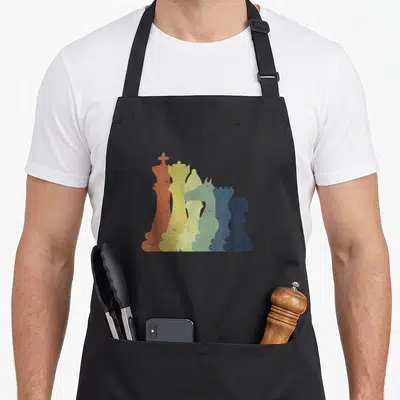 Chess dad mode apron - Six overlapping chess pieces in orange yellow green blue and dark blue arranged in descending — shown on a black cotton canvas apron against a white background