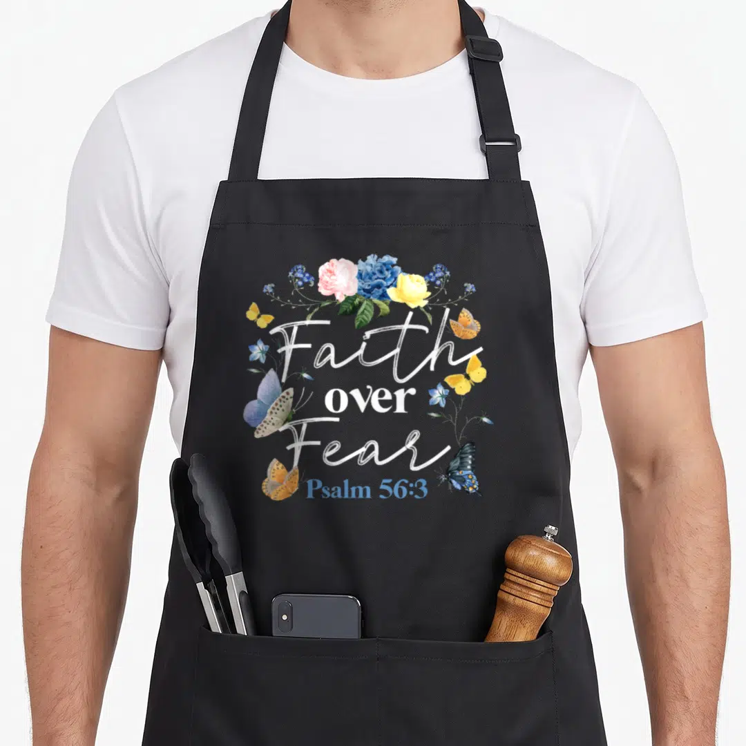 Fear flower bible verse apron - Faith over Fear Psalm 56:3 with watercolor flowers and butterflies in blue pink yellow — shown on a black cotton canvas apron against a white background