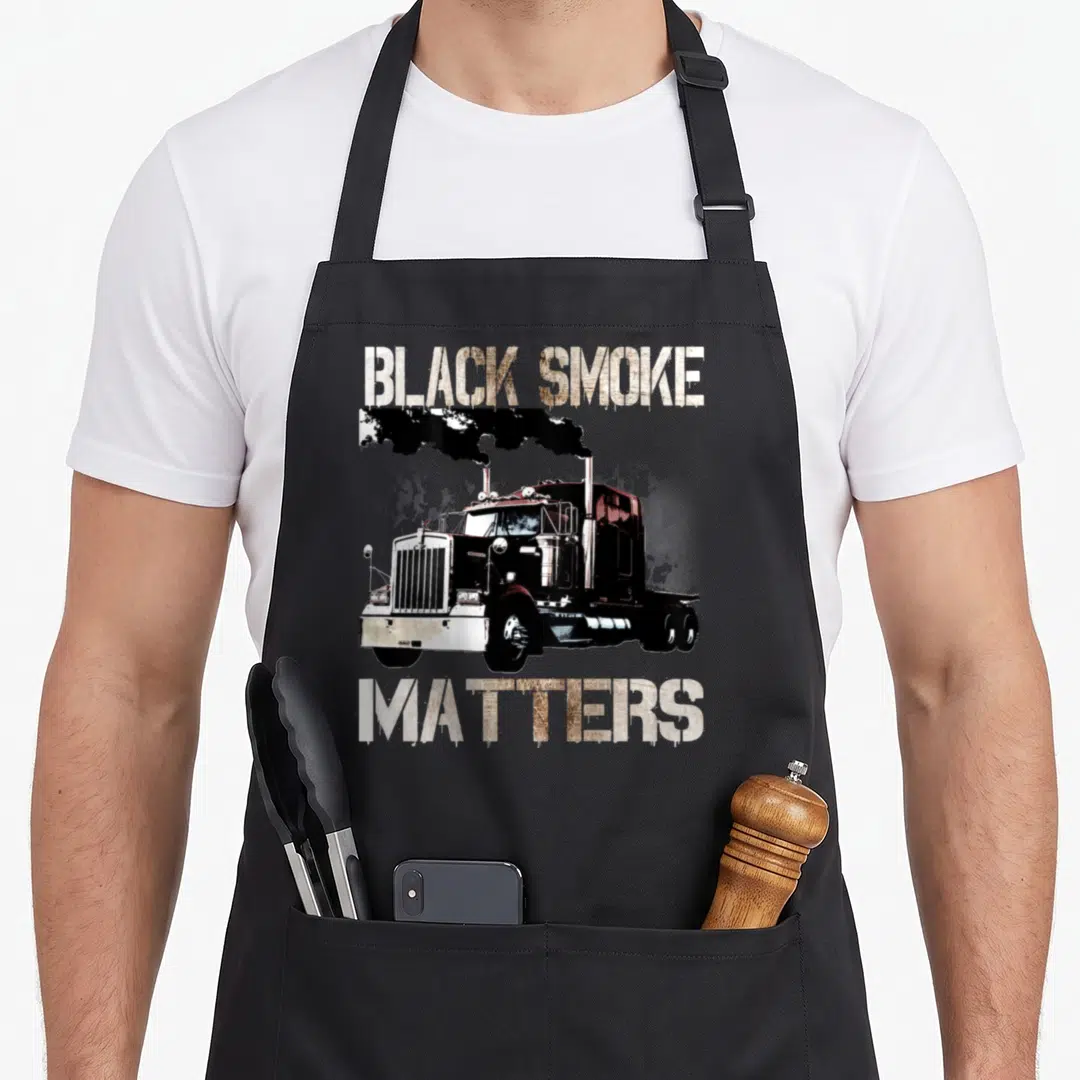 Trucker tractor trailer apron - Semi-truck with black exhaust smoke and text BLACK SMOKE MATTERS in white and brown — shown on a black cotton canvas apron against a white background