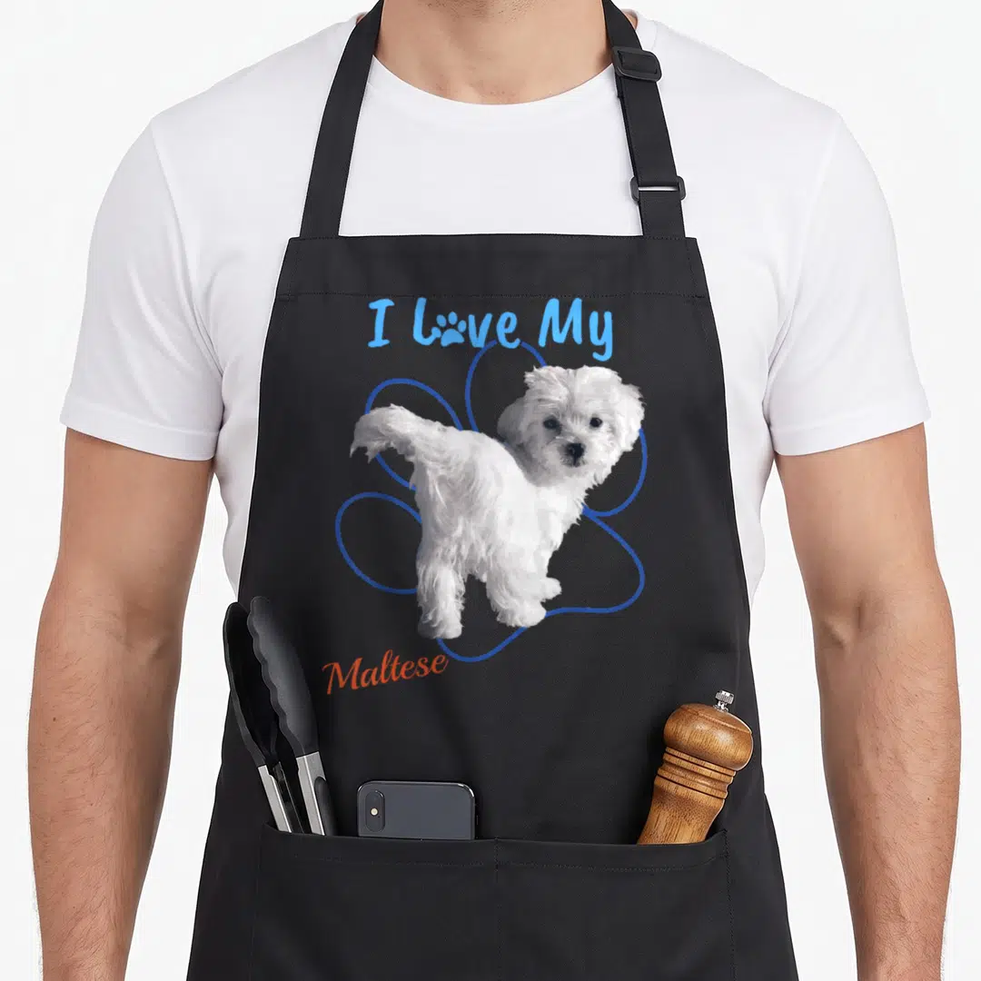 Maltese paw dog apron - I Love My Maltese text with white cartoon dog and blue paw print outline — shown on a black cotton canvas apron against a white background