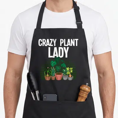 Retro gardening plant lady apron - CRAZY PLANT LADY text above five potted plants on green striped semi-circle — shown on a black cotton canvas apron against a white background