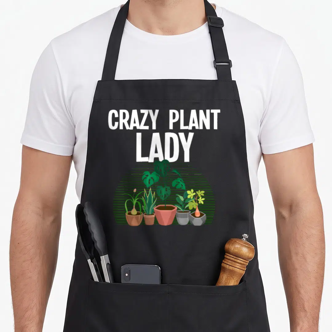 Retro gardening plant lady apron - CRAZY PLANT LADY text above five potted plants on green striped semi-circle — shown on a black cotton canvas apron against a white background