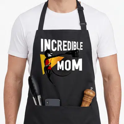 Incredible mom apron - Elastigirl punching forward with INCREDIBLE MOM text and geometric shapes — shown on a black cotton canvas apron against a white background