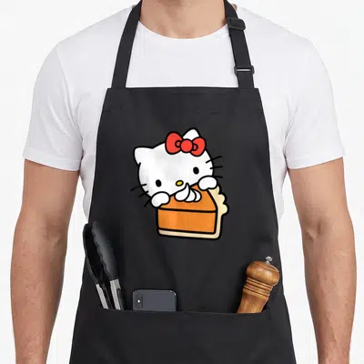 Slice pie apron - White cartoon cat with red bow holding orange cake slice with black outlines — shown on a black cotton canvas apron against a white background