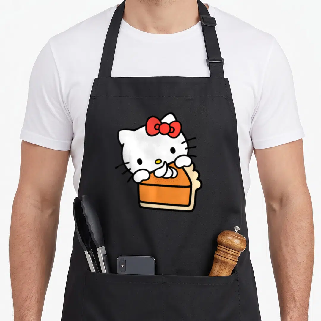 Slice pie apron - White cartoon cat with red bow holding orange cake slice with black outlines — shown on a black cotton canvas apron against a white background