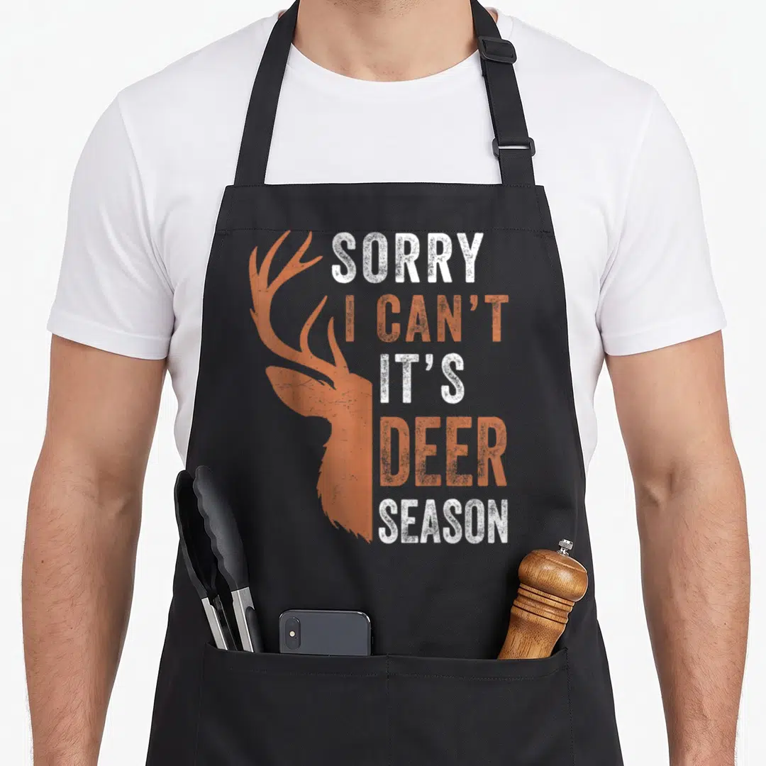 Sorry hunter apron - Distressed white and orange deer head silhouette next to stacked text reading sorry i can t — shown on a black cotton canvas apron against a white background