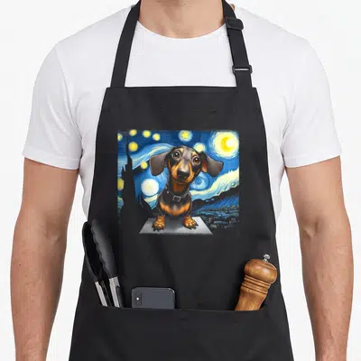 Dog sausage apron - Dachshund sitting on pedestal against swirling blue starry night sky in watercolor style — shown on a black cotton canvas apron against a white background