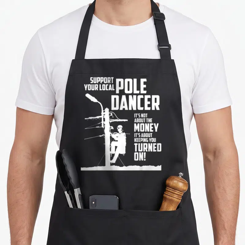 Support utility apron - White lineman climbing pole with SUPPORT YOUR LOCAL POLE DANCER text — shown on a black cotton canvas apron against a white background