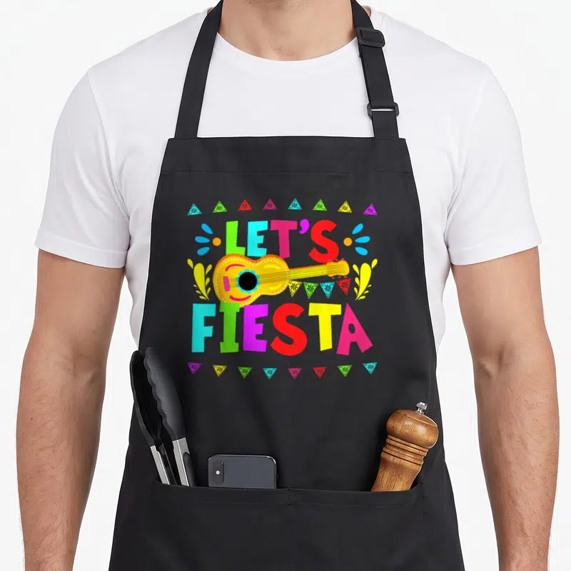 Fiesta cinco mexican apron - Cartoon guitar with LET'S FIESTA text, colorful bunting flags, and geometric triangles — shown on a black cotton canvas apron against a white background