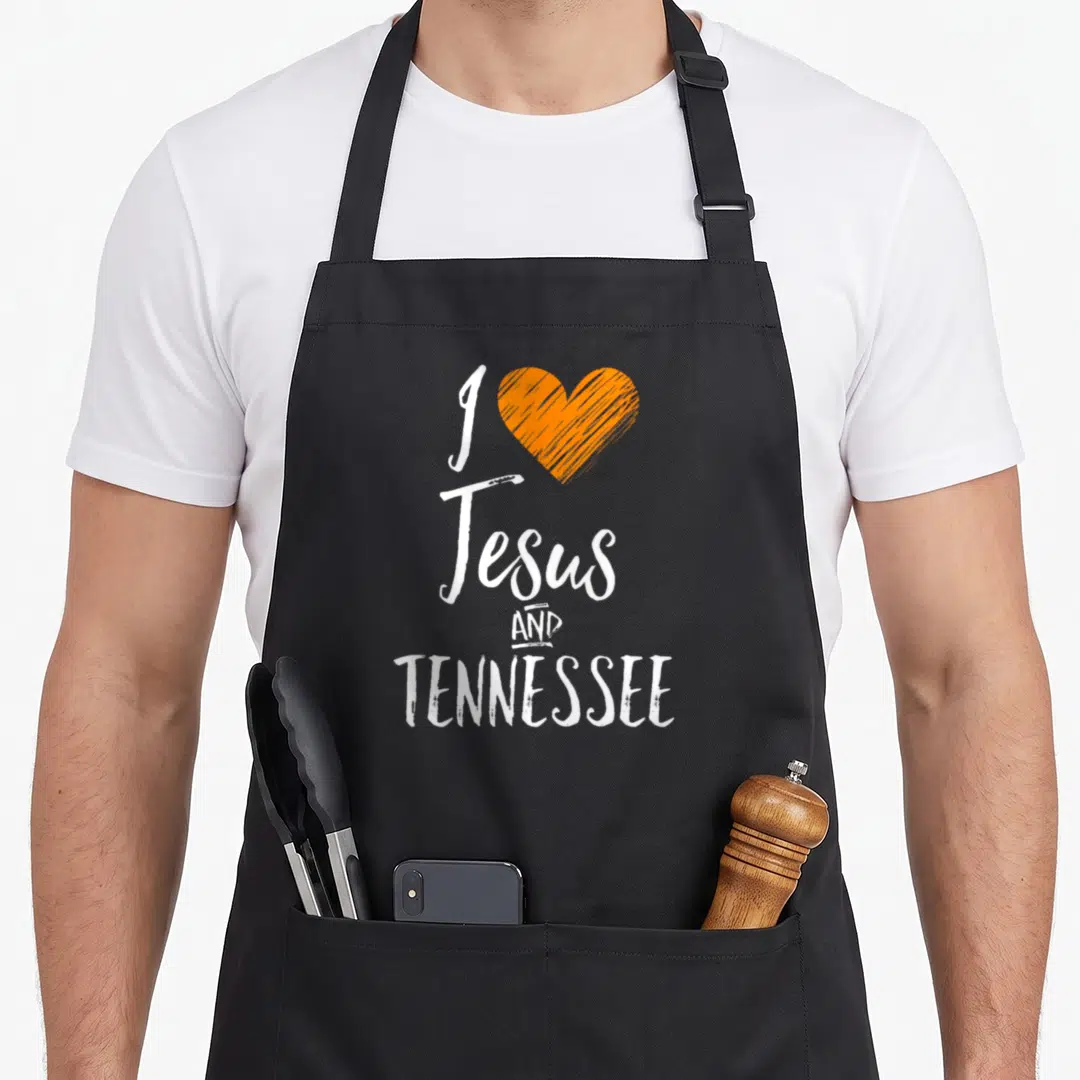 Jesus tennessee men women kids apron - White text I Jesus AND TENNESSEE next to an orange sketched heart — shown on a black cotton canvas apron against a white background