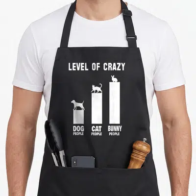 Outfit bunny apron - White bar chart reading LEVEL OF CRAZY with dog, cat, and bunny silhouettes on ascending columns — shown on a black cotton canvas apron against a white background