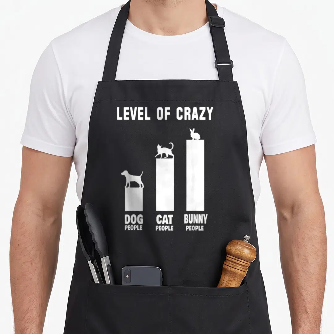 Outfit bunny apron - White bar chart reading LEVEL OF CRAZY with dog, cat, and bunny silhouettes on ascending columns — shown on a black cotton canvas apron against a white background